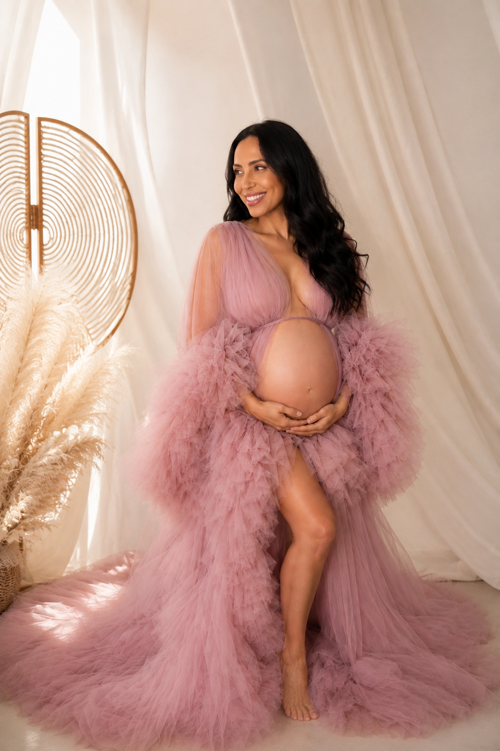 Expectant mother in a dusty rose ruffled tulle gown cradling her bump in a bright Toronto studio