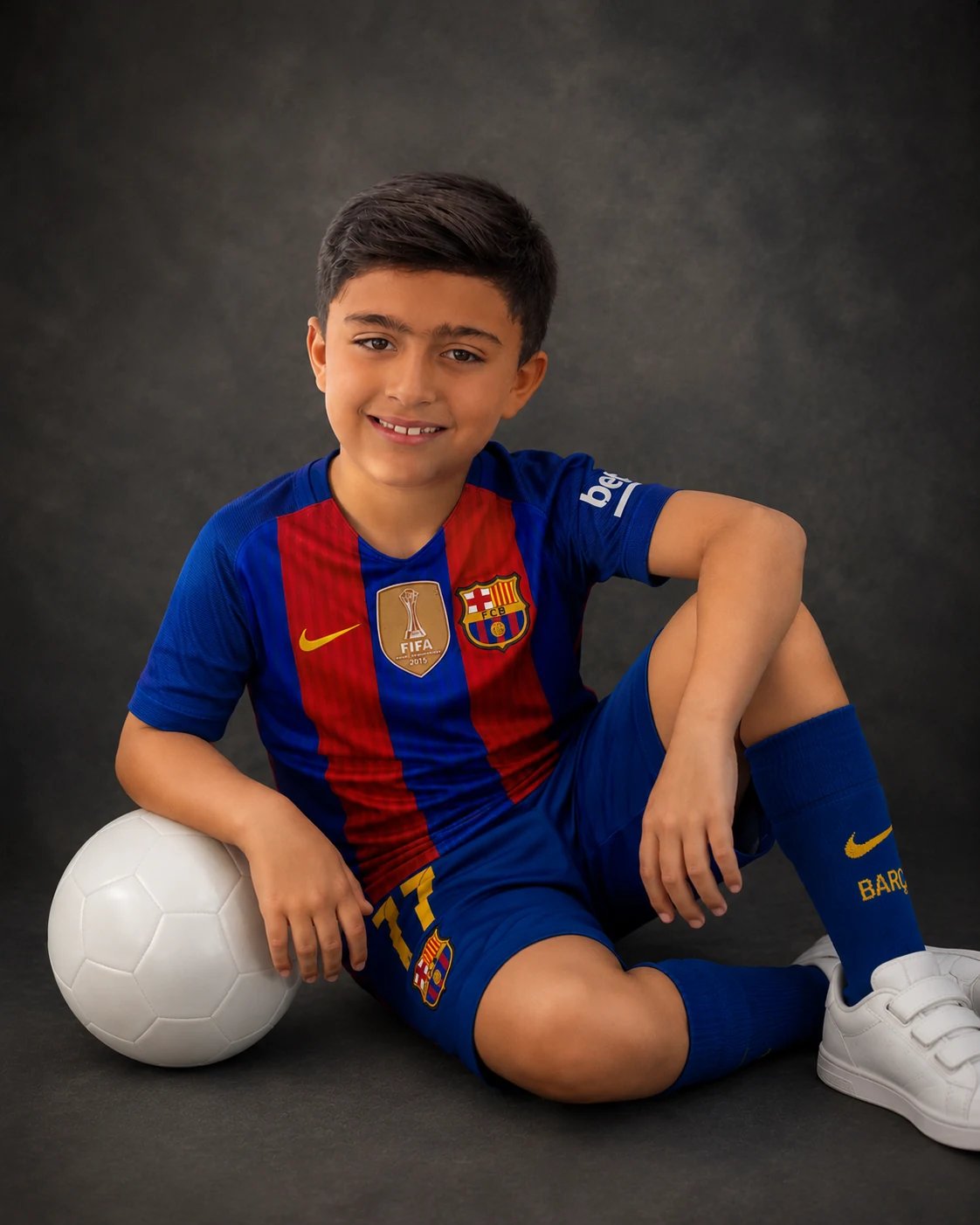 Young boy in a soccer kit seated with a ball in the North York studio, Toronto milestone photography