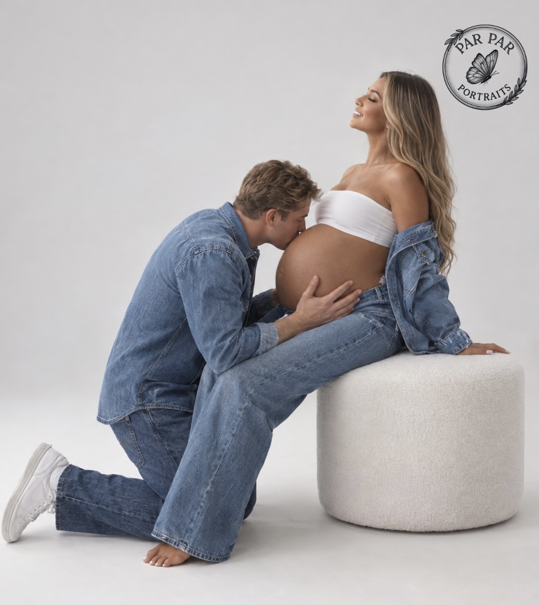 Partner kneeling to kiss the baby bump in matching denim during a Toronto maternity photography session